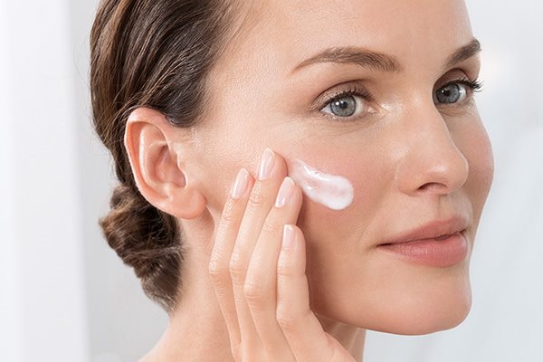 Žena nanosi kremu na lice.