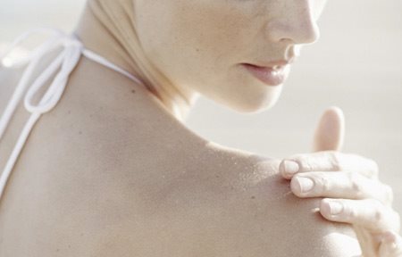 Žena nanosi kremu na desno rame.